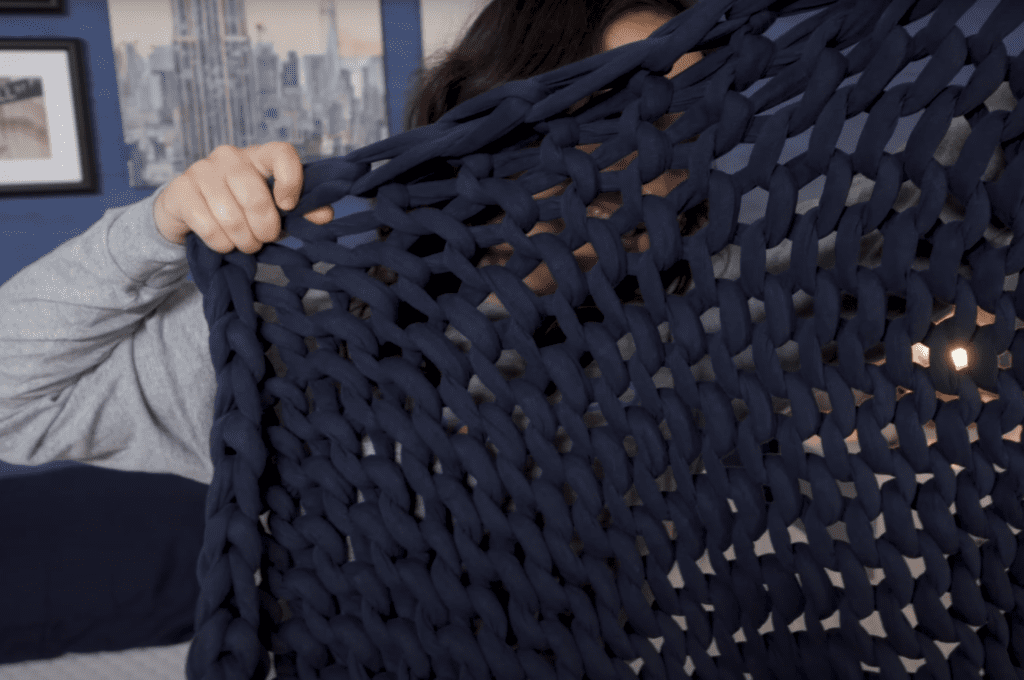 stretching Bearaby Cotton Napper's open-weave knit weighted blanket design