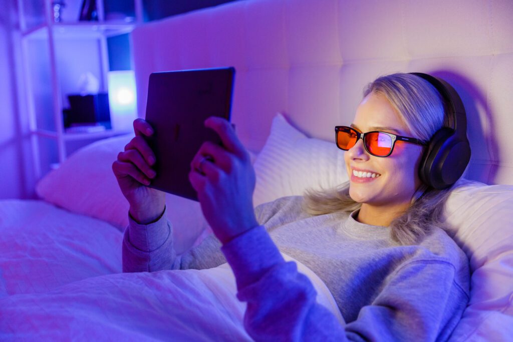 woman wearing swanwick blue light blocking glasses in bed