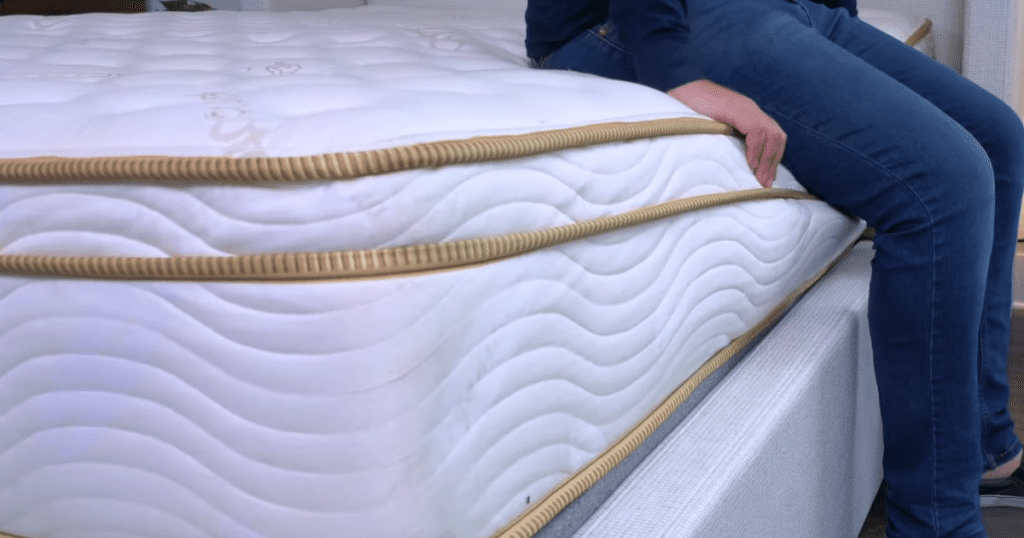 Photo showing someone sitting on the edge of the Saatva Classic with minimal compression